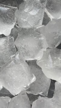 Camera flyover above large clear ice cubes macro texture. Vertical