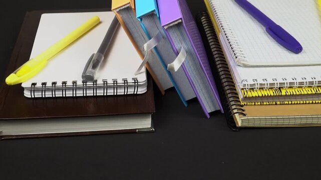 Various types of notepads and ballpoint pens lie on a black table. Sets for notations, studying, note -taking, and diary.