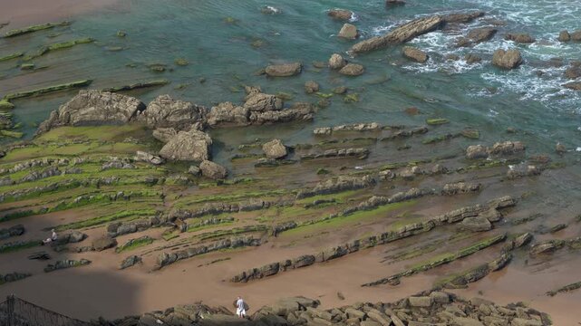 Person walking along the itzurun beach flysch cliffs