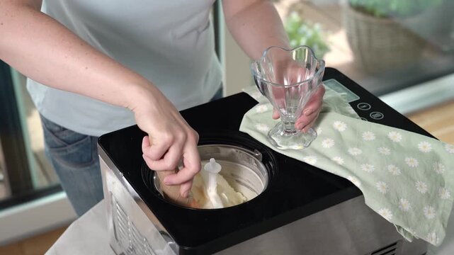 Serving homemade ice cream by scooping frozen dessert into elegant glass bowl. Refreshing sweet treat ready to eat