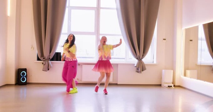 Female clowns. Cheerful rehearsal training. Smiling comedian in pink yellow color outfit performing dynamic show. Festive dance movement.