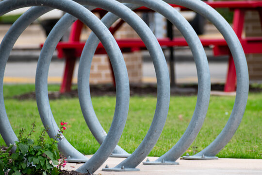 Four silver bike racks in front of a picnic table. 