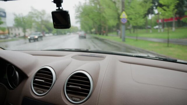 Interior view from a moving vehicle with windshield wipers clearing rainwater from the glass