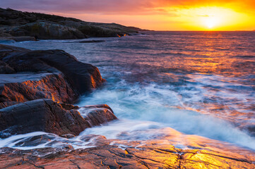 Fototapeta premium Coastal sunset view near Gothenburg in Sweden with waves crashing on rocks