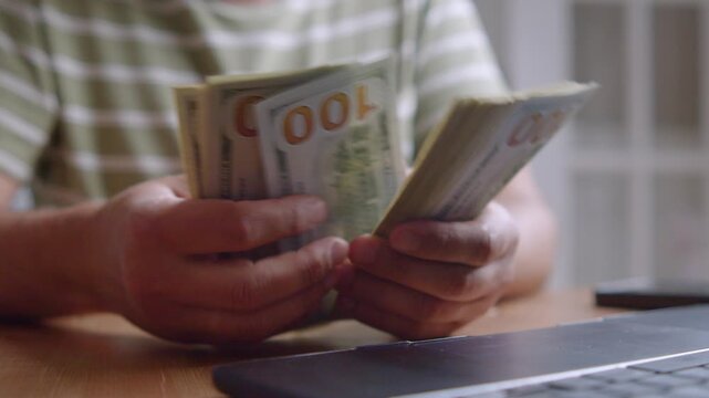 Hands methodically sort through stacks of cash in a cozy home setting. Sunlight streams through the window, creating a calming atmosphere of finance and focus