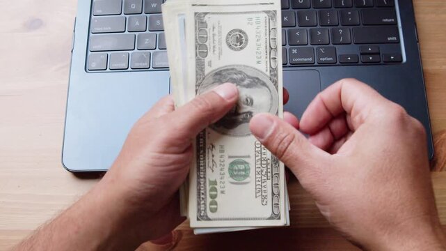 Hands expertly count stacks of hundred-dollar bills at a wooden desk, sunlight pouring in, creating a warm ambiance. Money management made simple and engaging