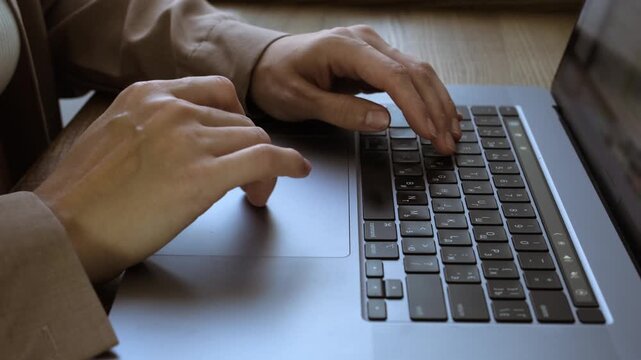Close-up of woman's hands typing and using trackpad on laptop