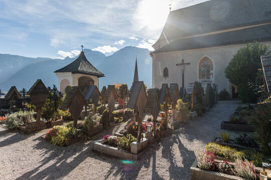 View of the historic Hallstatt Cemetery with its traditional graves and the Parish Church of Hallstatt, surrounded by majestic mountains. Hallstatt, Austria.