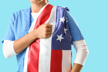 Fototapeta premium Female doctor with USA flag on blue background, closeup. Labor Day celebration
