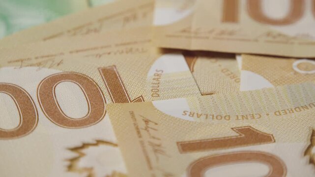 Nestled together, Canadian hundred dollar bills create a stunning visual display. The detailed artwork and bold hues bring money to life, captivating the viewer's attention