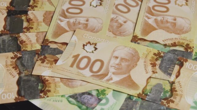 Luxurious Canadian bills of 100 glide over rich green and tan hues. Dark stones spark curiosity in this captivating arrangement of history and value