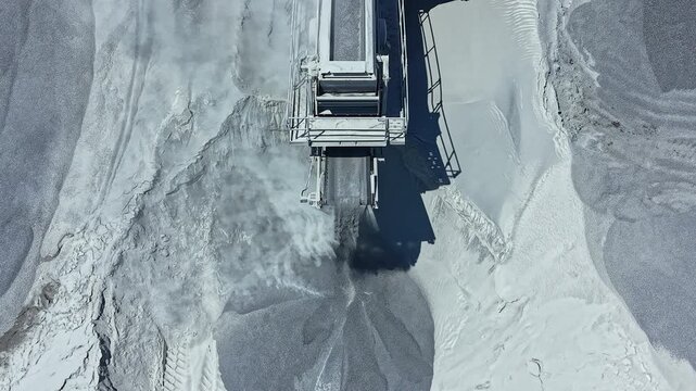 Heavy machinery works in a granite quarry to cut and extract stone. Dust rises as the machine moves, showing the labor involved in stone extraction.