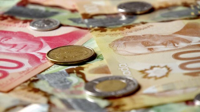 Brightly colored Canadian bills and coins spread across a smooth surface showcase their intricate designs. Each note tells a story of culture and connection