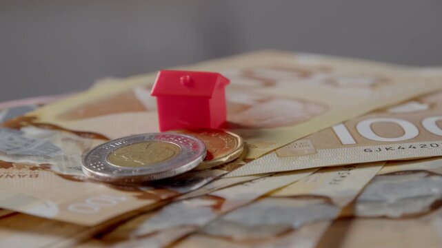 Colorful bills and coins create a vibrant canvas of wealth. A tiny house sits proudly among the currency, symbolizing dreams and aspirations for a bright future