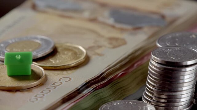 Hands gather coins and bills, sorting through Canadian currency in warm evening light, creating a colorful display of money and coins on the table