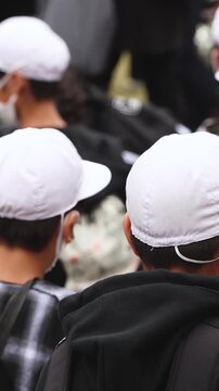 Group of school children students outdoor excursion, guided tour in the city with guide, docent with tourist pupils visitors, wear color caps hats, kids class field trip, urban sightseeing in Japan
