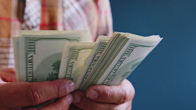 A man carefully counts stacks of dollar bills, weighing the necessary expenses for home repairs and planning how to allocate funds for materials