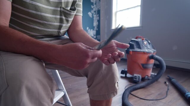 A man focuses intently on counting dollar bills to determine how much money he needs for essential home repair materials. The effort reflects a meticulous approach to budgeting