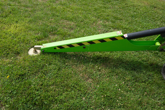 Outrigger arm and pressure plate of a hydraulic lift on a grassy surface.