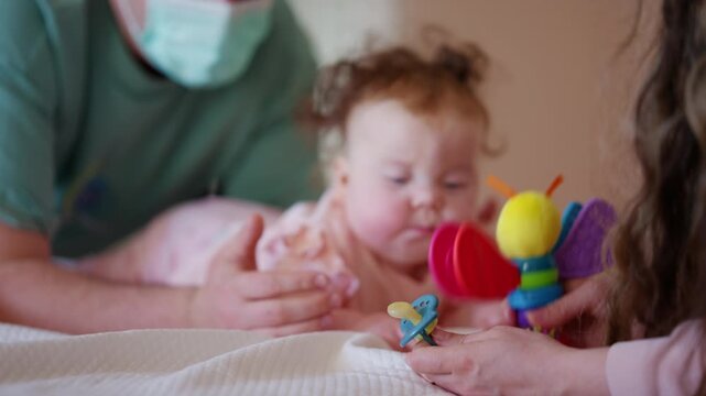 A baby lies comfortably while watching a colorful toy, and doing mobility exercises with a caregiver