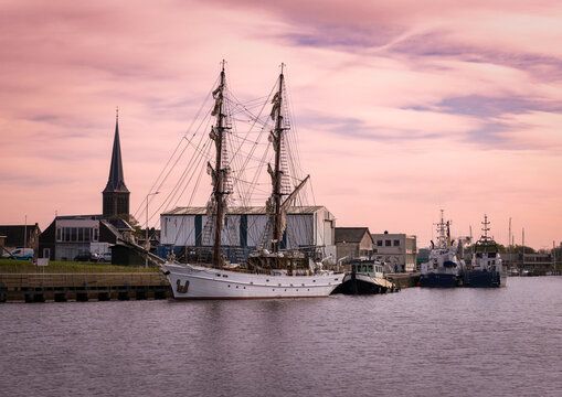 Traditional sailing boats moored in the harbor of Lemmer, Netherlands, with part of the historic town visible in the background. A peaceful maritime scene capturing Dutch coastal heritage.
