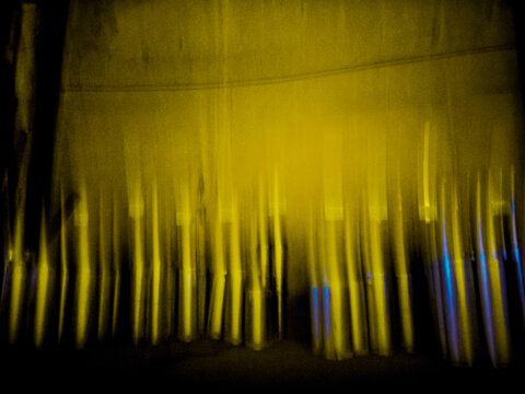 Intentional camera movement (ICM) photography of vertical light trails creating a molten gold liquid metal distortion.