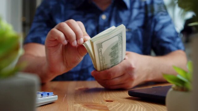 Close-up moments capture a man at home carefully counting stacks of dollars, emphasizing focus and precision in managing his finances