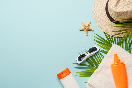 Sunscreen, towel and sunglasses on blue background.