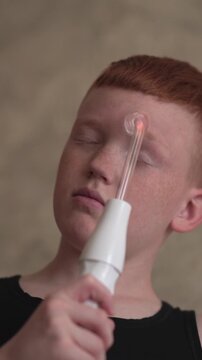 A teenager uses a Darsonval device on their face. Professional skincare at home. Teenage skin problems during hormonal changes. High quality FullHD footage