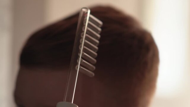 A teenager uses a Darsonval device for the scalp and face. Professional-grade skincare at home. Teenage skin issues during hormonal changes. High quality FullHD footage