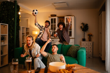 Friends cheering watching soccer together at home © Zoran Jesic