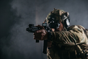 Fototapeta premium Tactical soldier aiming rifle during low light combat training with night vision helmet, smoky dark background and selective focus