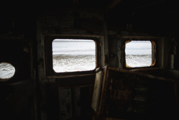 Abandoned ship wheelhouse interior with ocean view through portholes © Pavel Gorshkov