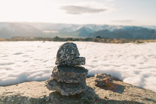 Stacked cairn on rocky mountain ridge with snow and distant peaks