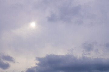 Fototapeta premium Moody overcast sky background with sun breaking through grey clouds