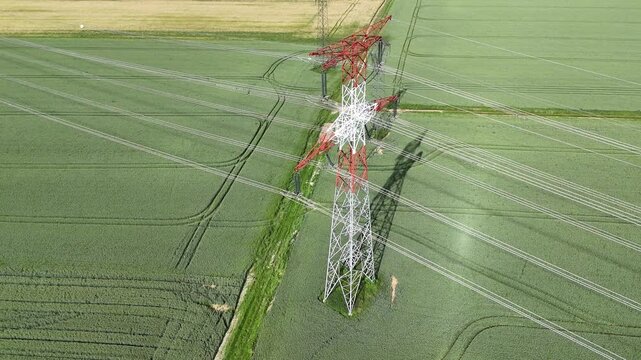 vue a&eacute;rienne d'un pyl&ocirc;ne &eacute;lectrique haute tension. La structure m&eacute;tallique est peinte en rouge et blanc, sur un fond vert de champs Les c&acirc;bles &eacute;lectriques sont bien visibles.
