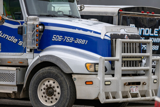 Campbellton, New Brunswick, 06 June 2026 : A Mundle's Towing heavy-duty truck with a blue and white stripe design stands parked.