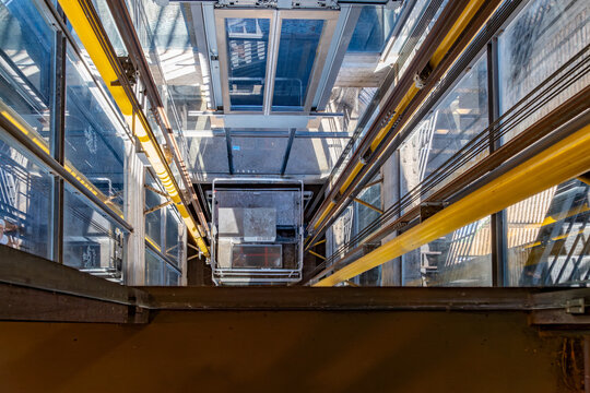 Glass elevator cab descending inside modern shaft