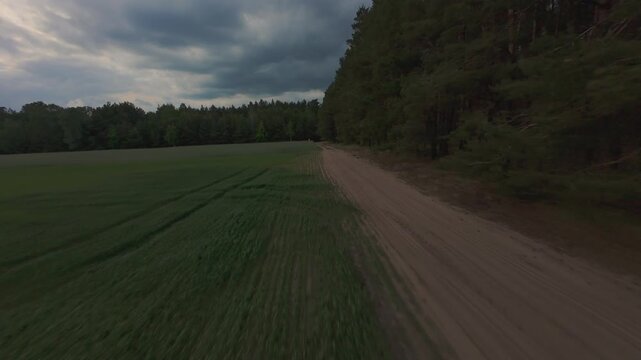 Aerial drone footage of rural road through cultivated fields and fores