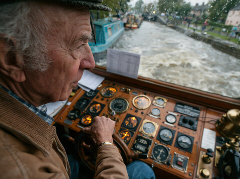 Elderly Man Mastery in Vintage Boat Steering on a Scenic Canal Cruise: Experience Leisurely River Navigation and Scenic Tourism Adventure
