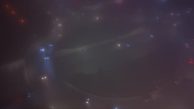 Nighttime underpass or trench-style highway with light traffic, viewed from above in foggy low-light conditions