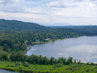 Fototapeta premium Lush Forested Hills and Riverside Homes Along a Calm Lake Near Mission BC Canada Panorama