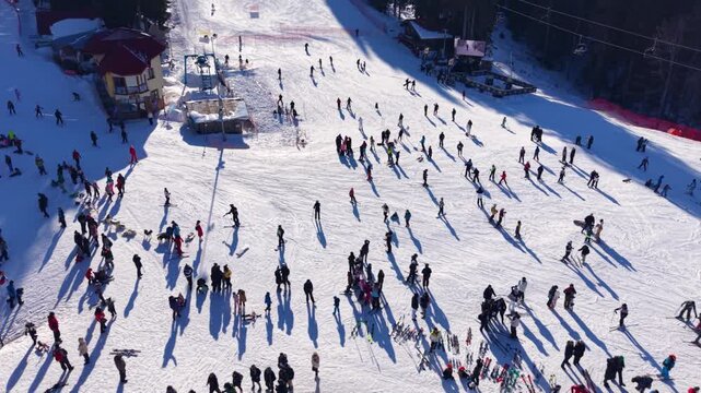 Ski lift station on a snowy slope with skiers waiting and riding, surrounded by pine trees in bright winter sunlight