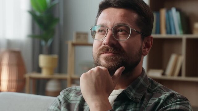 Caucasian happy smiling pensive man bearded guy in glasses at home thinking idea male thoughtful ponder smile think solution decide decision create indoor pondering hesitate unsure searching answer
