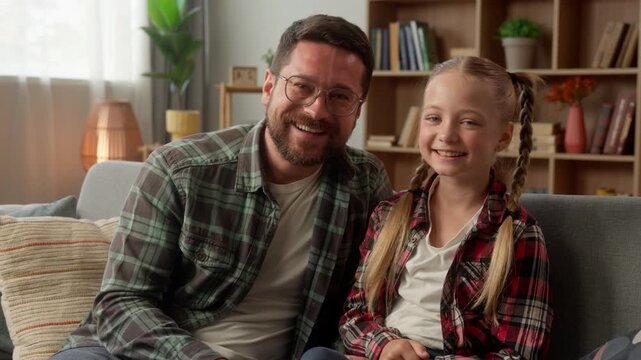 Happy family Caucasian dad giving high five little girl daughter clapping hands at home couch joyful male parent father carefree kid schoolgirl man guy support smiling child looking at camera indoors