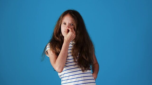 Young european teen girl covering nose from bad smell against blue background
