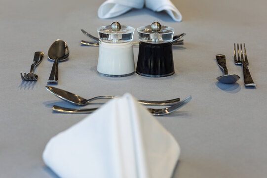 Salt and pepper shakers with silverware on restaurant grey  table cloth