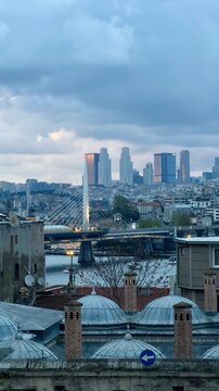 Vertical view of Halic metro bridge and modern Levent skyscrapers over stone chimneys of Suleymaniye Mosque in Istanbul, Turkey. Ancient Ottoman empire buildings and contemporary city architecture.