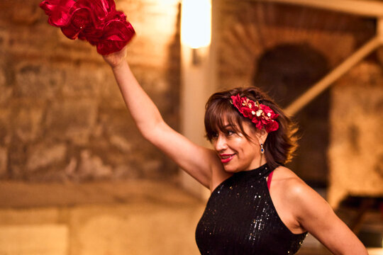 Beautiful mature woman in makeup and formal attire, waving her red handkerchief and dancing sensually and enthusiastically to the cueca brava, a traditional Chilean dance, part of the national holiday
