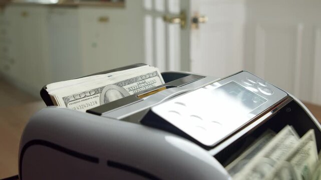 Observe the fascinating process of bills being counted effortlessly by a sleek machine in a warm and inviting office environment, showcasing efficiency and technology